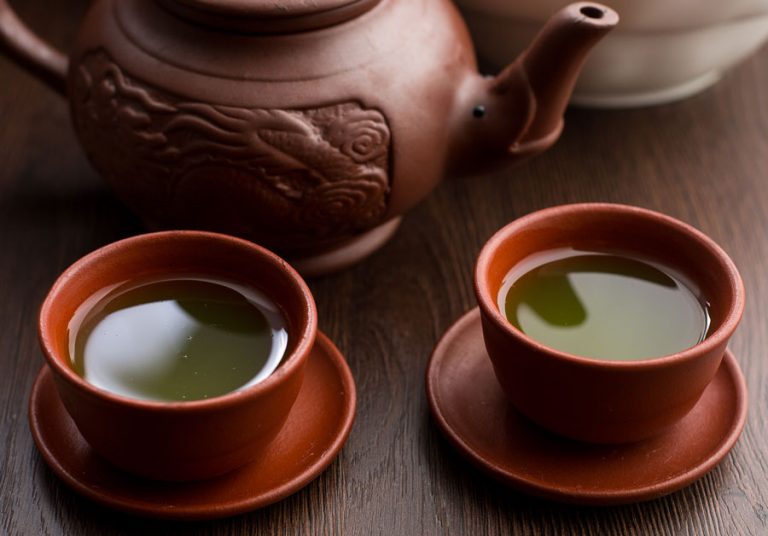 Delta 8 green tea served in two cups on a wooden table with delta tea bags.